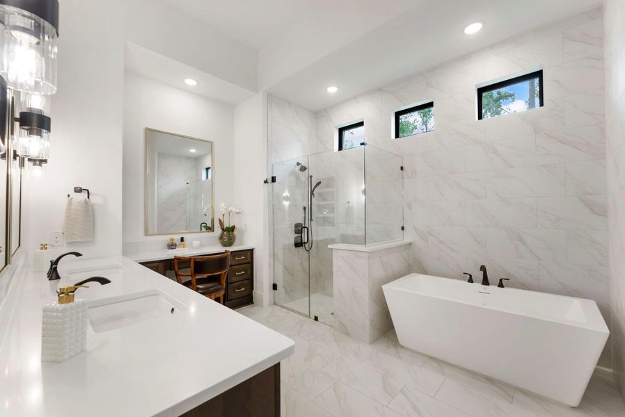 Customized from the builder standard with upgraded finishes and a spa-like layout. A freestanding tub, oversized shower, and elevated tile selections create a bright, polished retreat.