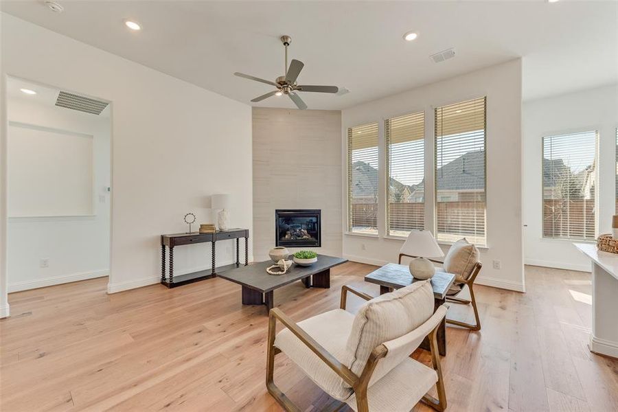 Living room featuring a tiled fireplace, ceiling fan, and light hardwood / wood-style flooring