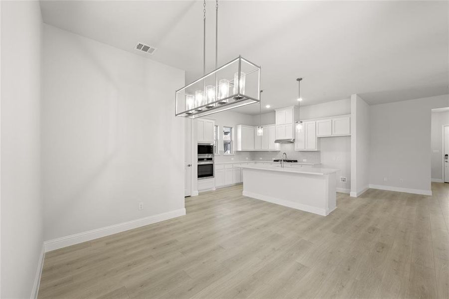 Kitchen featuring white cabinets, a center island, light hardwood / wood-style floors, and pendant lighting