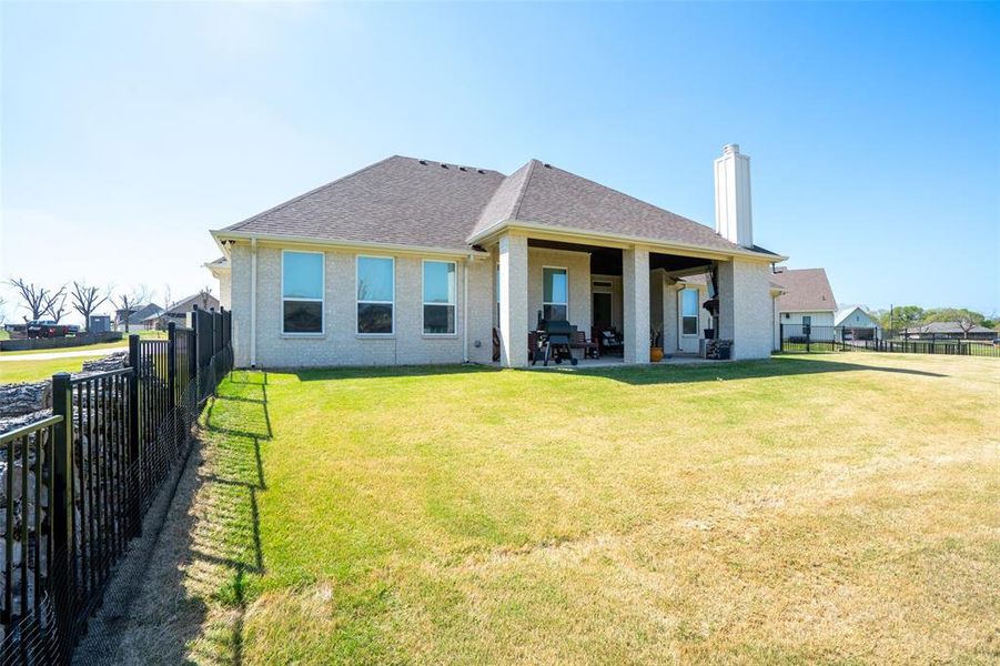 Back of house with a chimney, a patio, a fenced backyard, roof with shingles, and brick siding Back of house with a chimney, a patio, a fenced backyard, roof with shingles, and brick siding