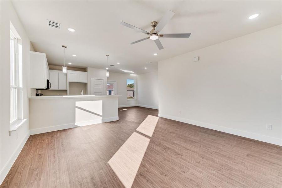 Unfurnished living room featuring ceiling fan and light hardwood / wood-style floors