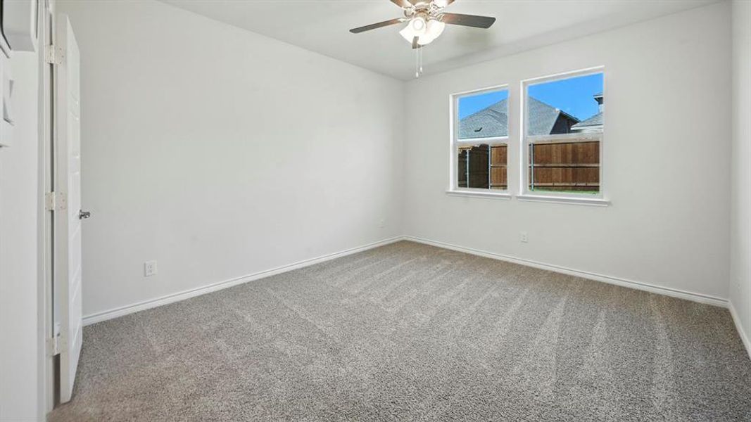 Carpeted spare room with baseboards and a ceiling fan Carpeted spare room with baseboards and a ceiling fan