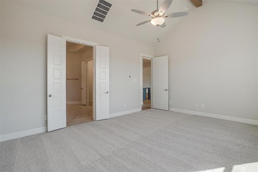 Unfurnished bedroom with ceiling fan, high vaulted ceiling, beam ceiling, and light colored carpet