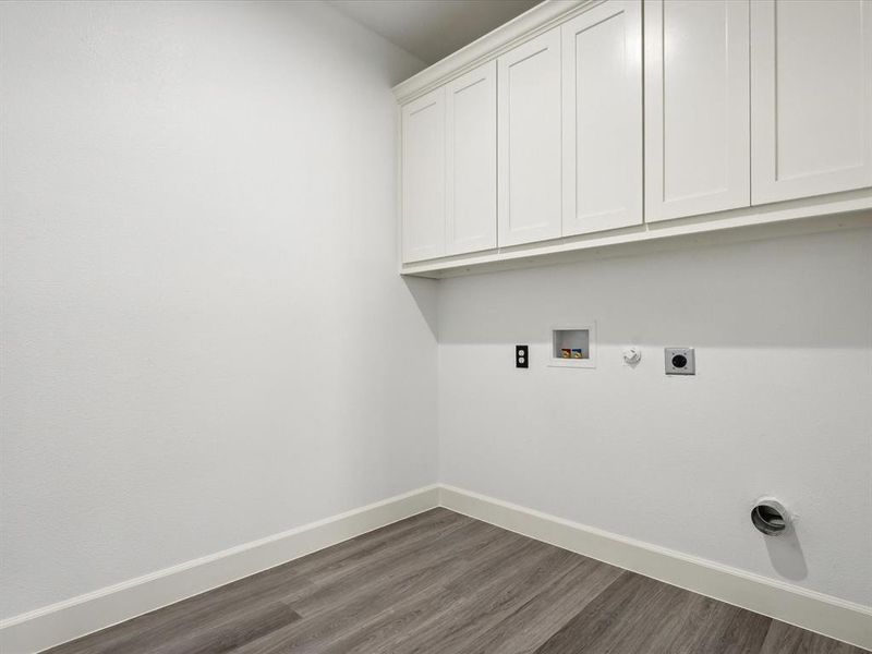 Laundry area featuring cabinets, hookup for a washing machine, hardwood / wood-style floors, and electric dryer hookup