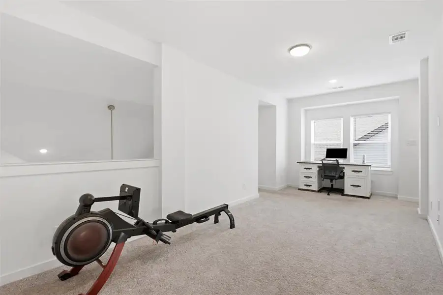 Versatile bonus room featuring light gray carpeting, abundant natural light from double windows, and recessed lighting