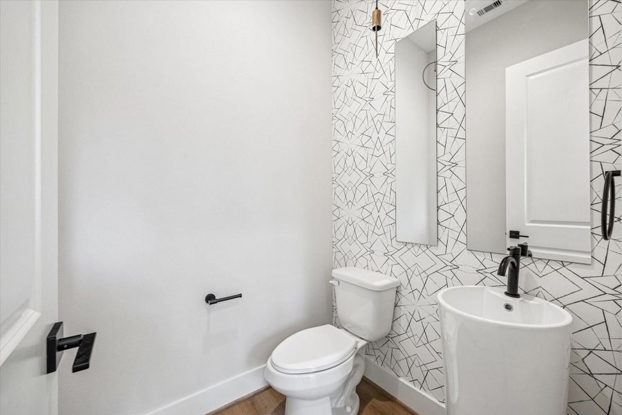 Powder bath conveniently located on the 2nd floor with a fun wallpapered accent wall, light fixture and pedestal sink.