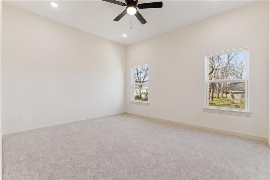 Carpeted spare room with ceiling fan and plenty of natural light