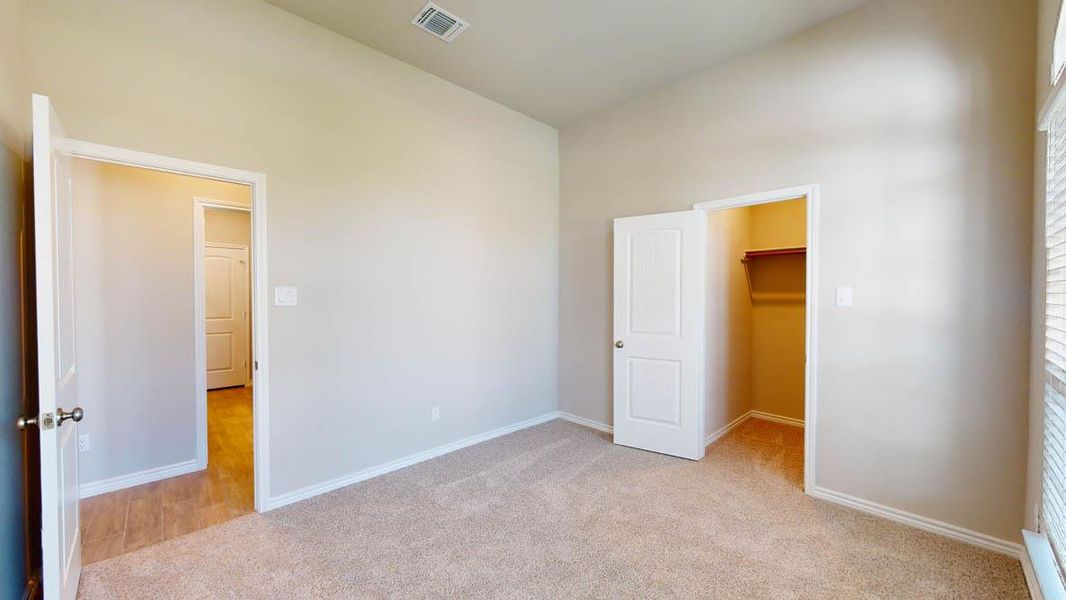 Unfurnished bedroom featuring a spacious closet, light colored carpet, and lofted ceiling