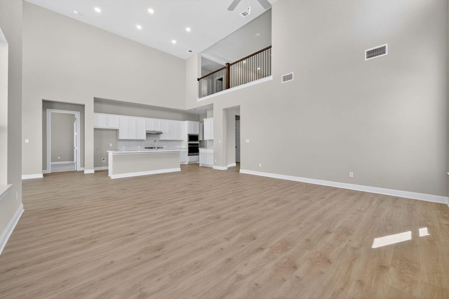 Unfurnished living room featuring light wood-style flooring, a high ceiling, and recessed lighting