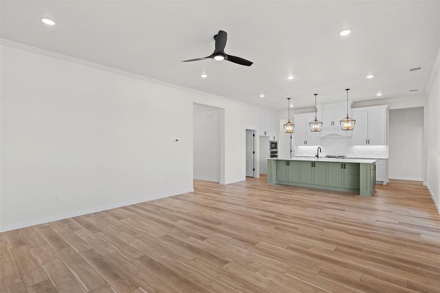 Unfurnished living room featuring recessed lighting, crown molding, light wood finished floors, and a ceiling fan