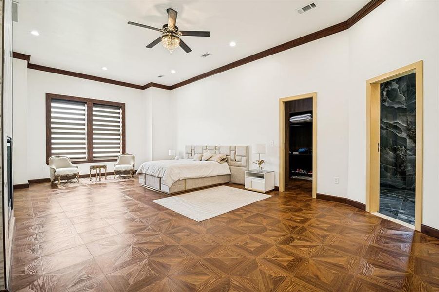 Primary Bedroom with patterned wood-finish flooring, wood trim, fireplace, seating area,