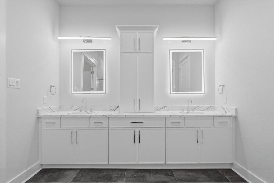 The primary bathroom features elegant quartz countertops and soft-close cabinet doors for quiet functionality, along with modern lighting and backlit mirrors that provide excellent illumination.
