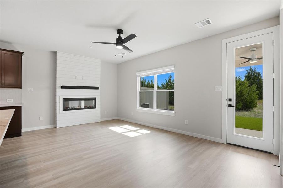Unfurnished living room featuring a ceiling fan, light wood finished floors, and a fireplace Unfurnished living room featuring a ceiling fan, light wood finished floors, and a fireplace