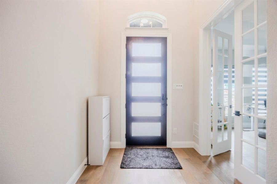 Entryway featuring french doors, baseboards, and light wood-style floors