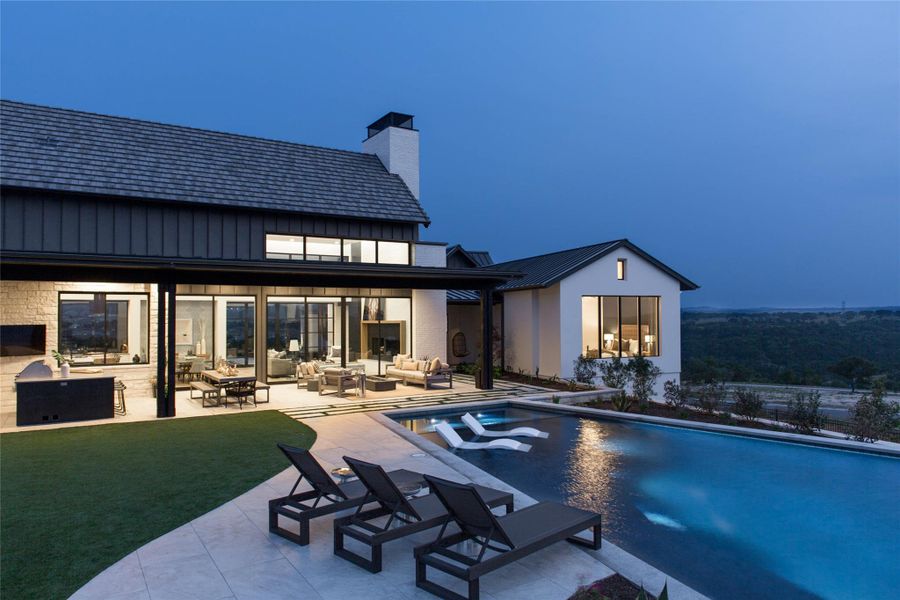 Back of property with an outdoor hangout area, an outdoor pool, a patio area, a chimney, and board and batten siding