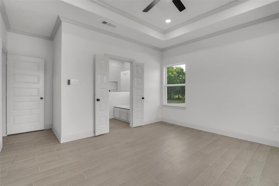 Unfurnished bedroom featuring ornamental molding, light wood-style floors, recessed lighting, a ceiling fan, and a raised ceiling Unfurnished bedroom featuring ornamental molding, light wood-style floors, recessed lighting, a ceiling fan, and a raised ceiling