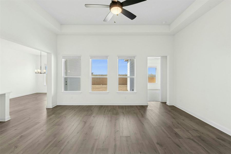 Spare room featuring a ceiling fan, dark wood finished floors, a high ceiling, and hanging lights