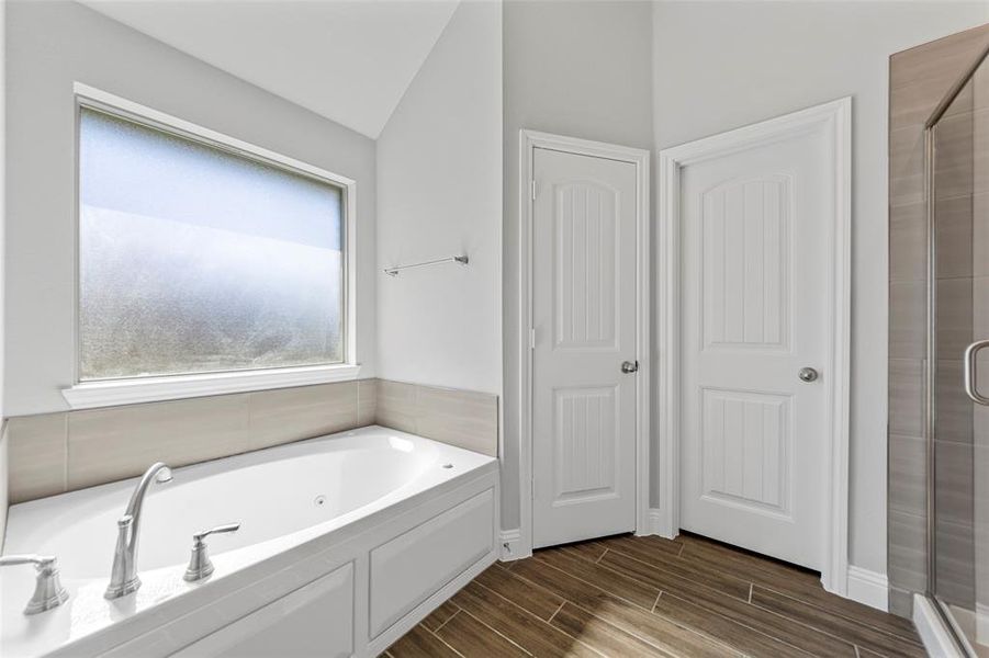 Bathroom featuring hardwood / wood-style floors, lofted ceiling, and shower with separate bathtub