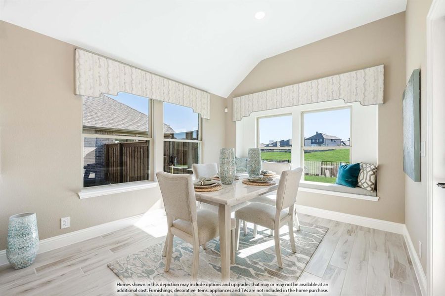 Bright dining area with vaulted ceiling, four-chair table, window seat, and light wood floors Bright dining area with vaulted ceiling, four-chair table, window seat, and light wood floors