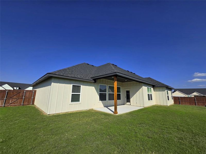 Back of property with roof with shingles, a fenced backyard, a patio, and board and batten siding Back of property with roof with shingles, a fenced backyard, a patio, and board and batten siding