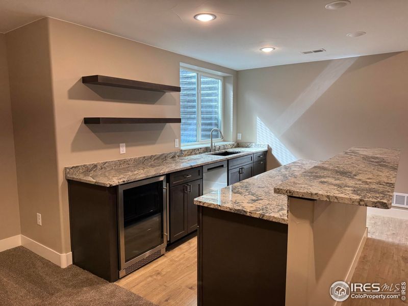 Basement includes this beautiful wet bar with mini fridge and dishwasher, granite countertops and floating shelves.