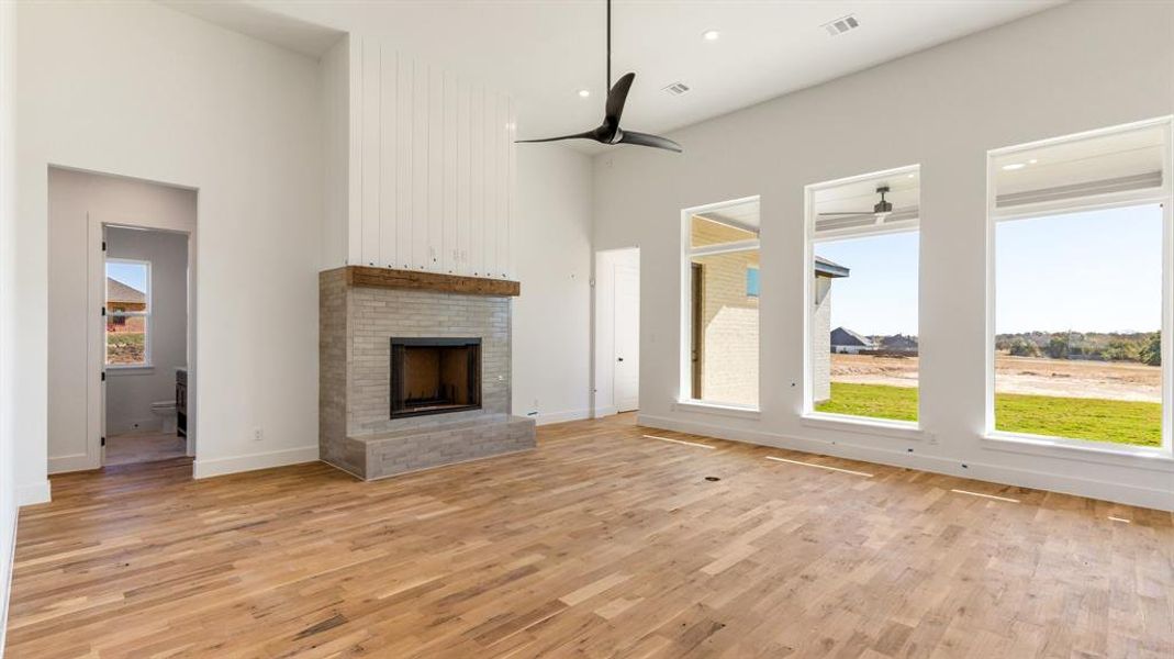 Unfurnished living room with ceiling fan, light wood-type flooring, and a fireplace