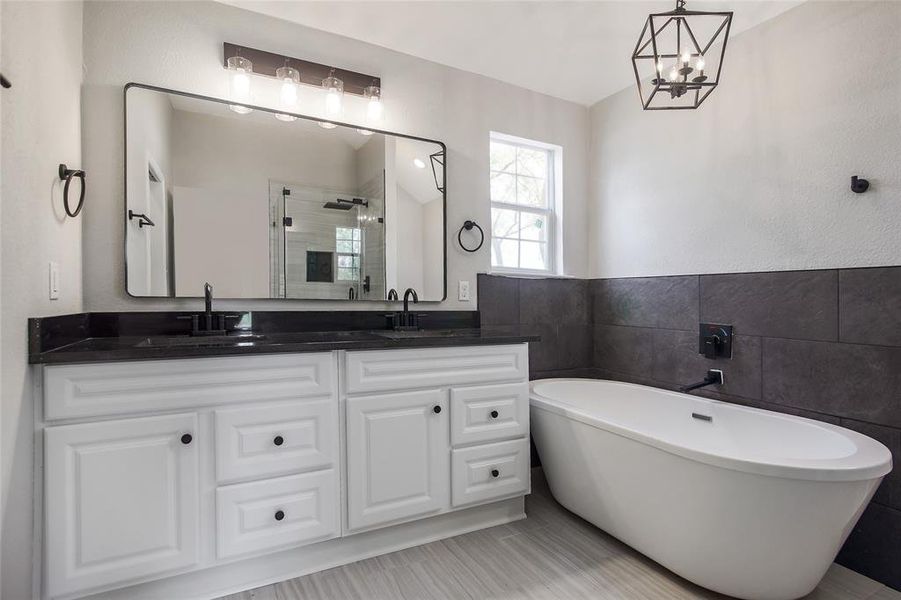 Featuring a lovely dial vanity with quart countertop, a stylish mirror, and elegant designer fixtures and hardware.