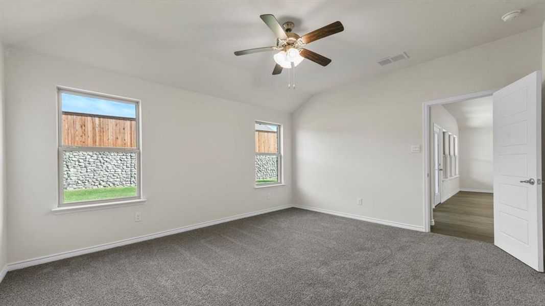 Spacious room with vaulted ceilings and gray carpet flooring