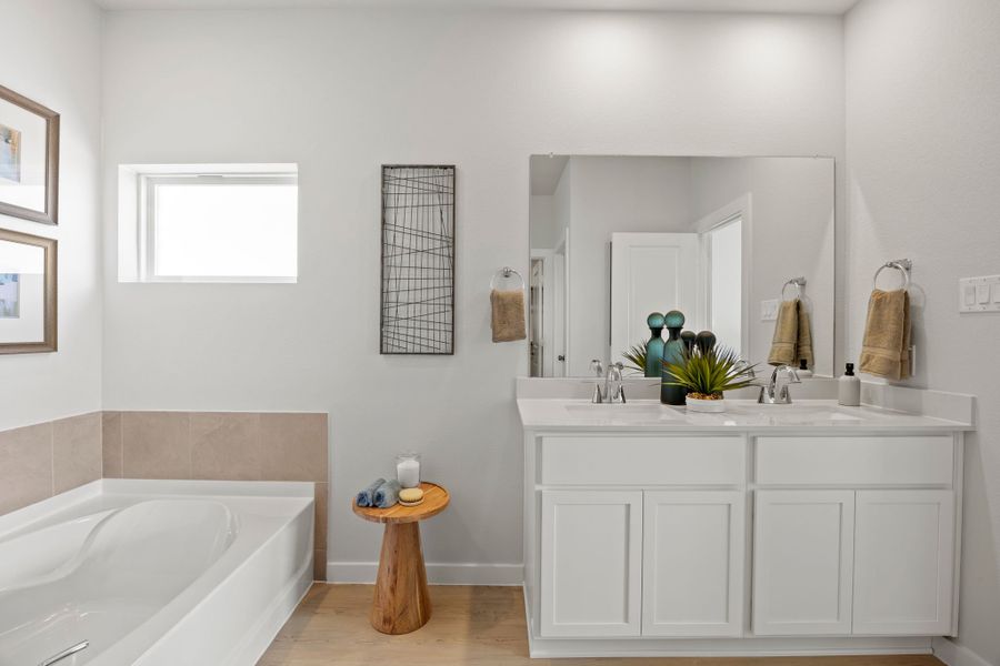 A bathroom with a tub sink and mirror.