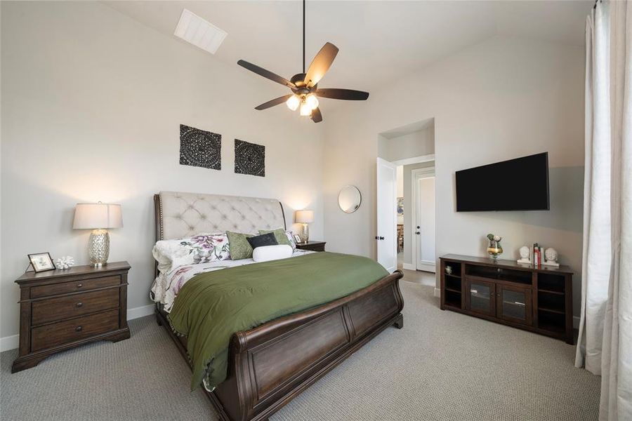 Bedroom with ceiling fan, lofted ceiling, and light carpet