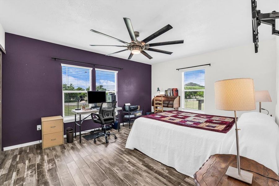 Primary bedroom featuring an office area, dark wood-style floors, and a ceiling fan