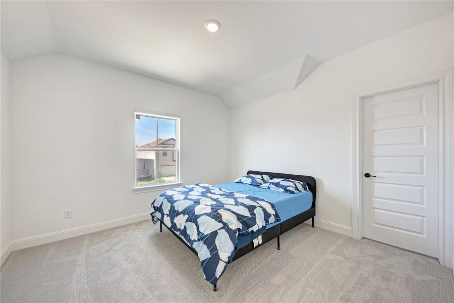 Carpeted bedroom featuring a single window, white paneled door, vaulted ceiling, and recessed lighting