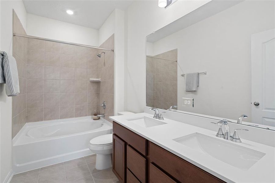 This primary bathroom is definitely move-in ready! Featuring an oversized tub/shower combo with tile surround, stained cabinets with light countertops and dual vanities, high ceilings, custom paint, sleek and modern finishes.