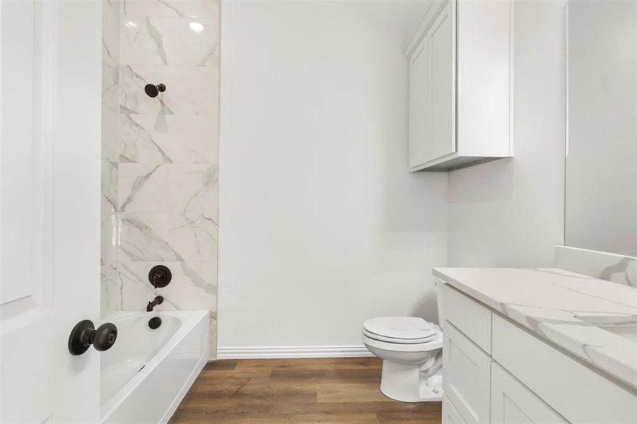 Full bathroom featuring wood-type flooring, vanity, toilet, and tiled shower / bath