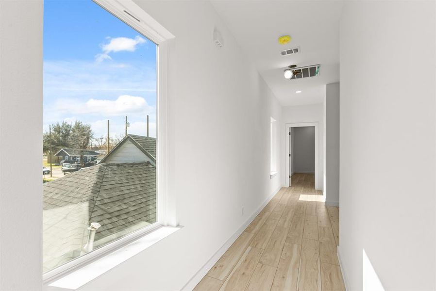 Hall featuring light wood finished floors, visible vents, and baseboards