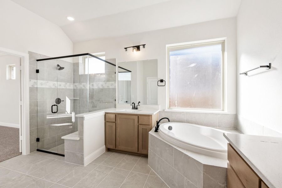 Master bathroom with corner soaking tub, glass walk-in shower, and wood vanity on tile floors