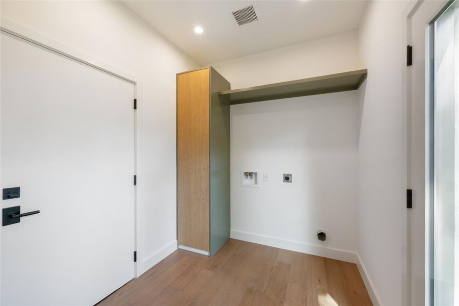 A dedicated laundry space offers practical utility connections and elegant wood flooring. A dedicated laundry space offers practical utility connections and elegant wood flooring.