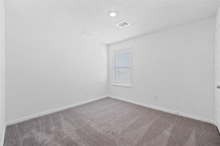 Secondary bedroom features plush carpet, neutral paint, lighting, large window with privacy blinds, and a walk-in closet.