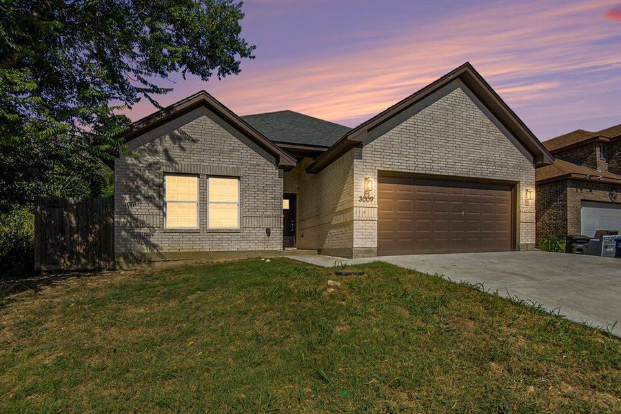 View of front facade featuring an attached garage, driveway, and brick siding