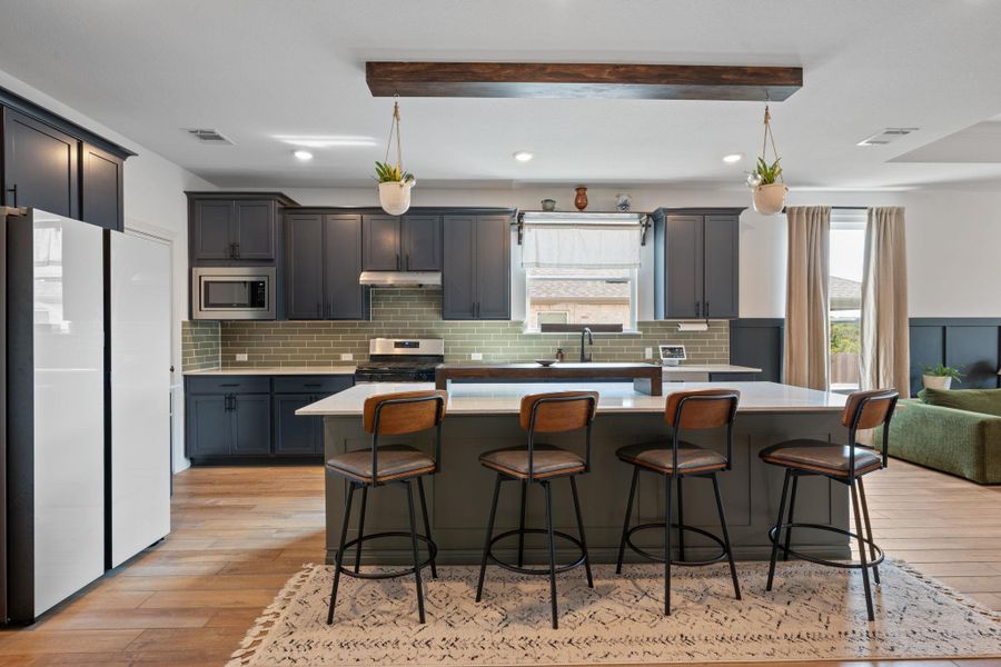 Kitchen with a kitchen island, stainless steel appliances, a kitchen bar, tasteful backsplash, and recessed lighting Kitchen with a kitchen island, stainless steel appliances, a kitchen bar, tasteful backsplash, and recessed lighting