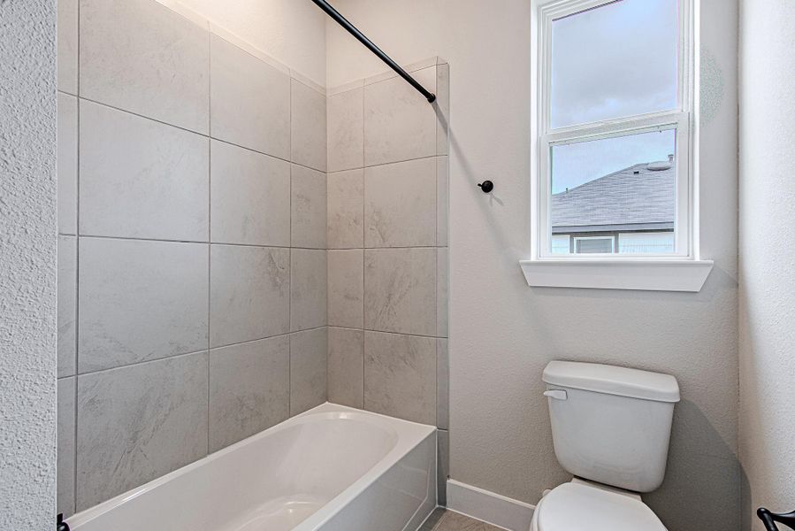 Bathroom with tiled shower and window for natural light.