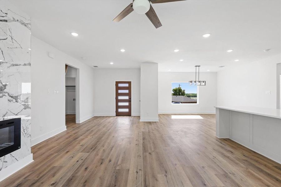 Unfurnished living room with light wood-type flooring, a fireplace, ceiling fan, and heating unit