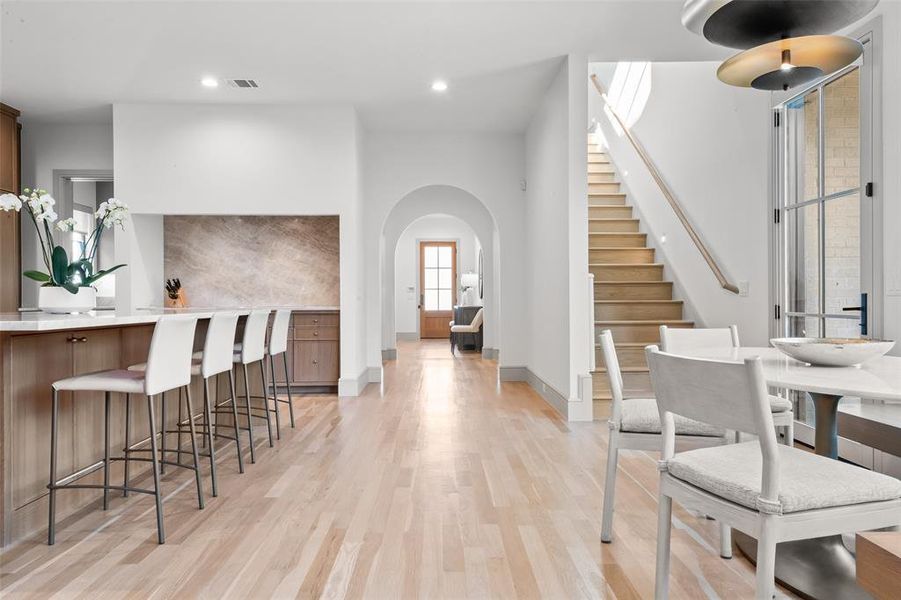 Dining area featuring light wood-type flooring, arched walkways, and recessed lighting