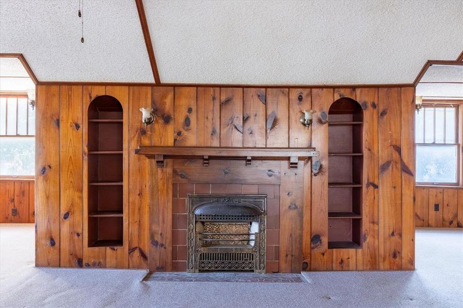 Unfurnished living room with a textured ceiling, a tile fireplace, carpet floors, and a wealth of natural light