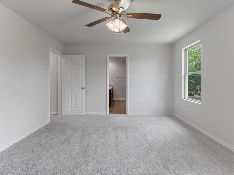 Spacious master bedroom with cozy carpet and a modern ceiling fan. Spacious master bedroom with cozy carpet and a modern ceiling fan.