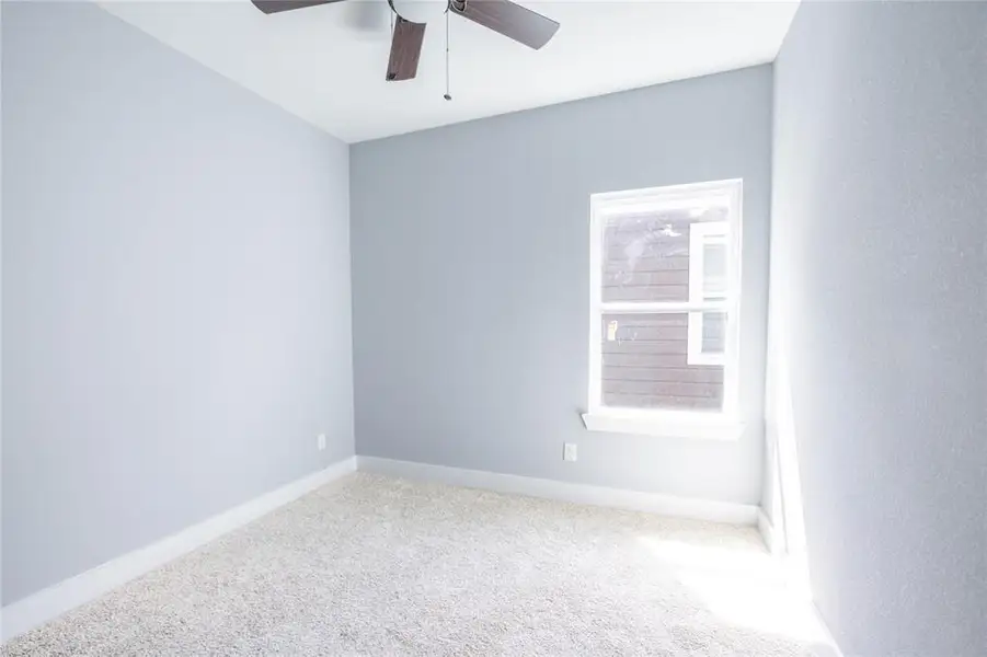 Carpeted empty room with baseboards and a ceiling fan