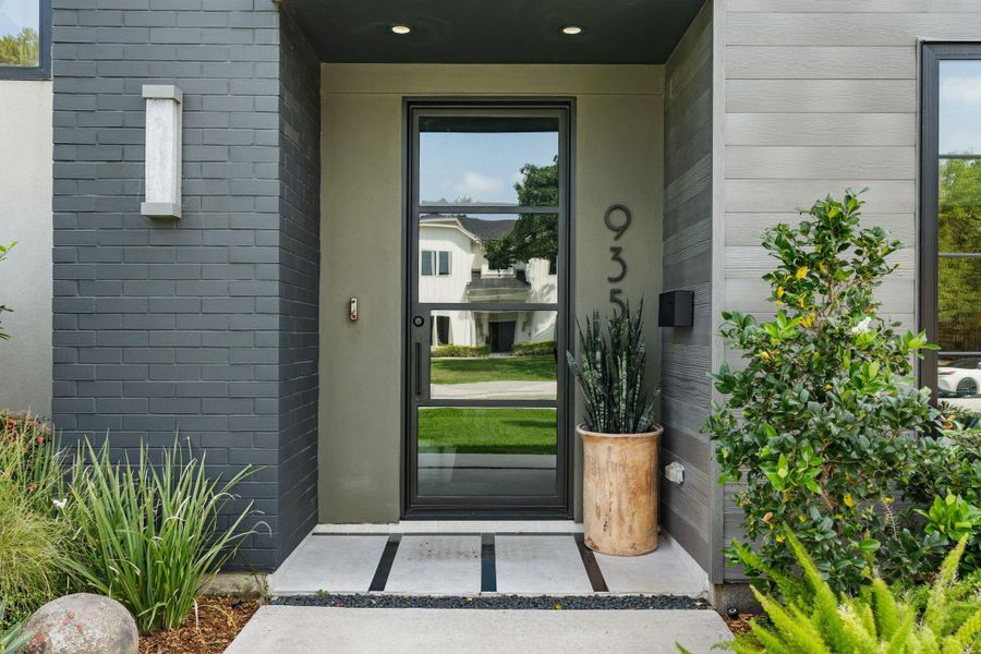 The covered front entry features a tinted glass paneled front door that adds privacy while setting the tone for the home's contemporary design.