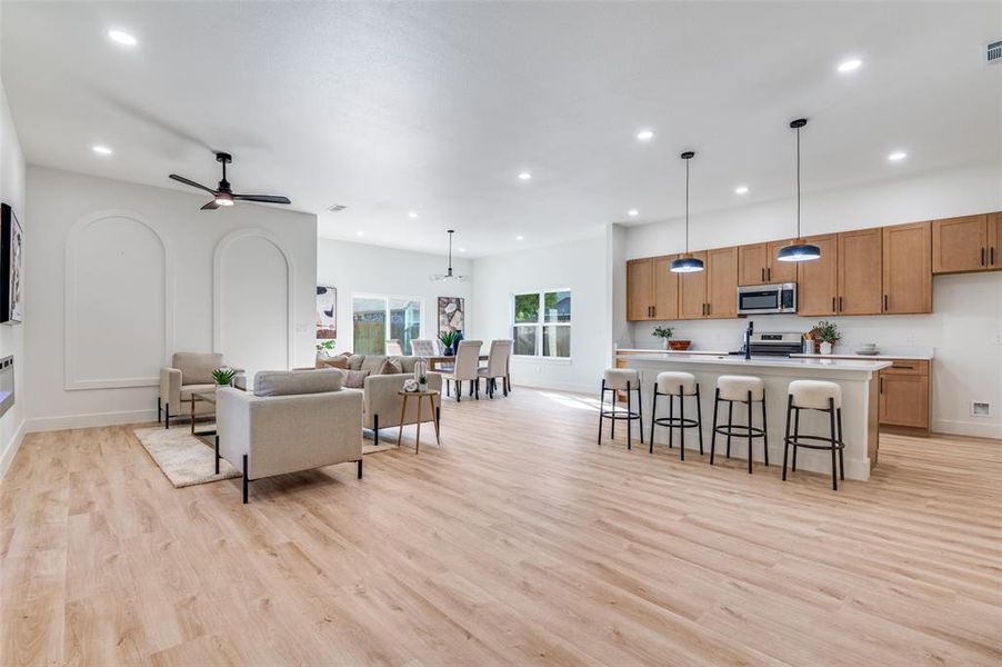 Living room with light wood finished floors, recessed lighting, and a ceiling fan Living room with light wood finished floors, recessed lighting, and a ceiling fan