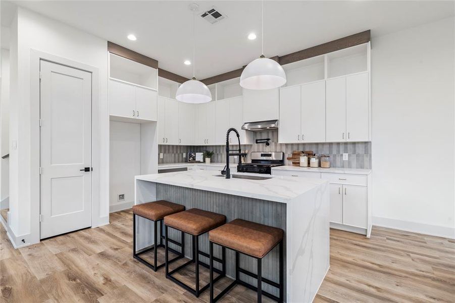 A beautifully designed chef’s kitchen boasting a large waterfall island with quartz countertops and bar seating.