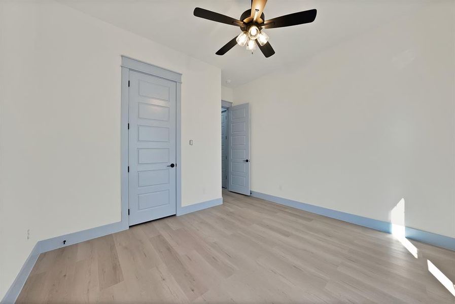 Unfurnished bedroom featuring light wood-style flooring, a closet, and ceiling fan